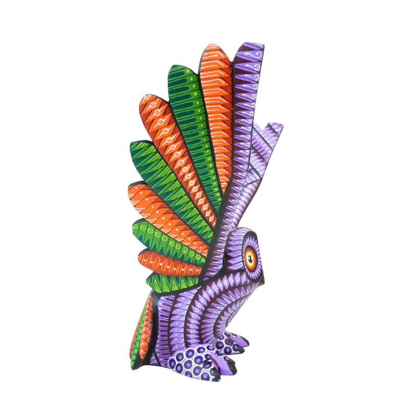 Colorful owl figurine with green, orange, and purple feathers on a white background