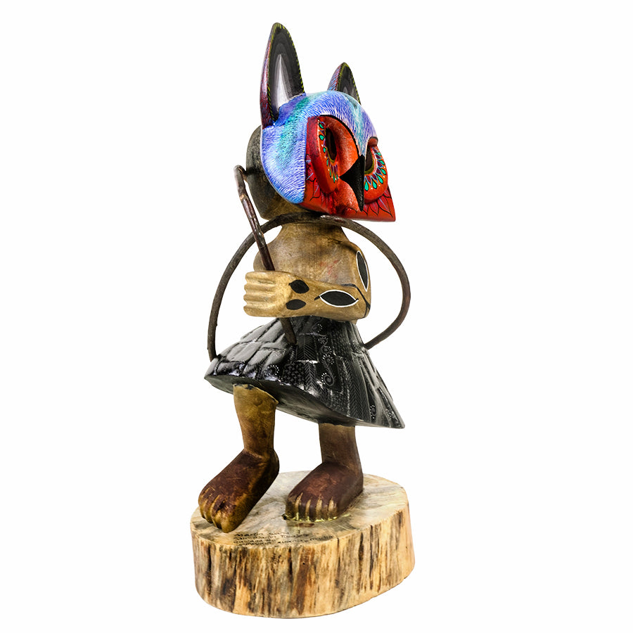 A hand-carved wooden dancer figurine with a colorful painted head, standing on a natural wood stump base against a white background.