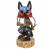 A hand-carved African-style wooden animal masked figurine with a colorful painted owl head, black textured skirt, and natural wood base, isolated on a white background.