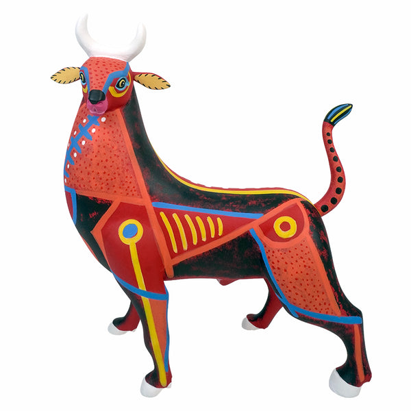 A handcarved , hand-painted Mexican copal wood sculpture of a bull, featuring a vibrant red and black body with geometric patterns in yellow, blue, and white, set against a plain white background.