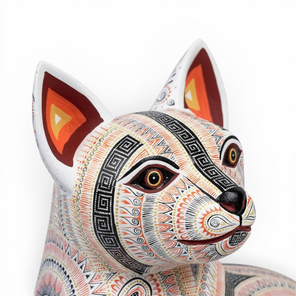 Cat sculpture made of wood with tribal patterns on a white background