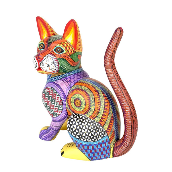 A colorful hand-painted Mexican-alebrije cat figurine with intricate geometric and floral patterns in red, orange, yellow, green, purple, blue, and black, set against a plain white background.