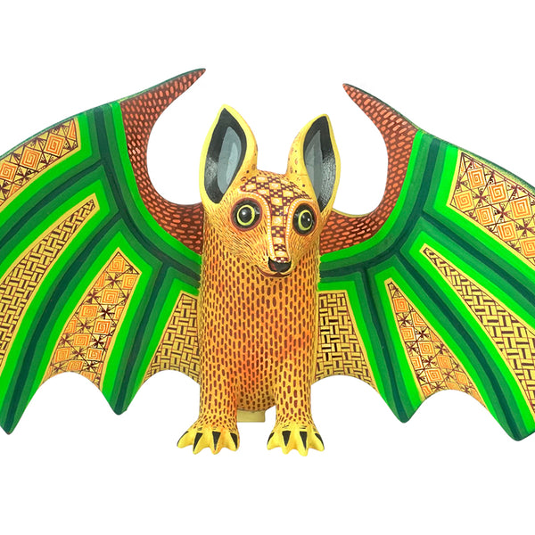 Alebrije woodcarving of a bat with golden yellowgreen wings on a white background