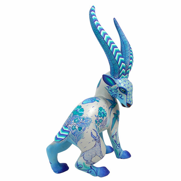 Mexican wood gazelle figurine, decorated with intricate blue and teal patterns on a white base, set against a plain white background.