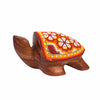 A wooden turtle-shaped decorative Huichol art, with a colorful beaded conch featuring a red, orange, yellow, and white floral pattern, set against a plain white background.