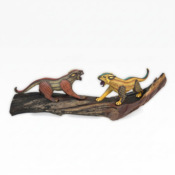 Handcarved copal wood art with two stylized jaguars on a wooden branch against a white background