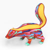 Vibrant copal wood skunk figurine with a multicolored hand painted pattern on a white background