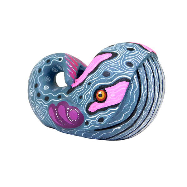 A stylized wooden figurine of a little whale with a gray body, pink and purple accents, and a curled tail.