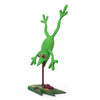 A green textured copal wood frog figurine posed upside down on a dark brown pole with a decorative leafy base, isolated on a white background.
