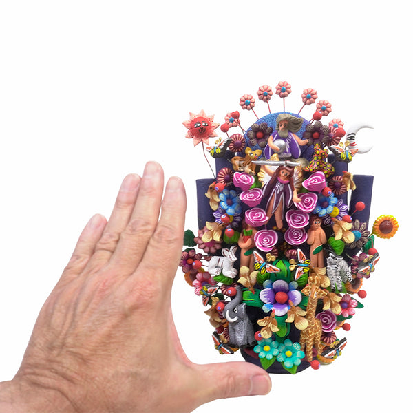 Full view of a hand-painted clay Tree of Life sculpture by the Juan Hernandez family, depicting the Creation story with God at the top holding a globe, a sun and moon on either side, an angel with a sword, Adam and Eve, and Garden of Eden animals throughout.