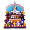 A colorful Day of the Dead ceramic ofrenda featuring sugar skulls, day of the dead bread, bananas, liquor, a molcajete, and flowers on a purple base.